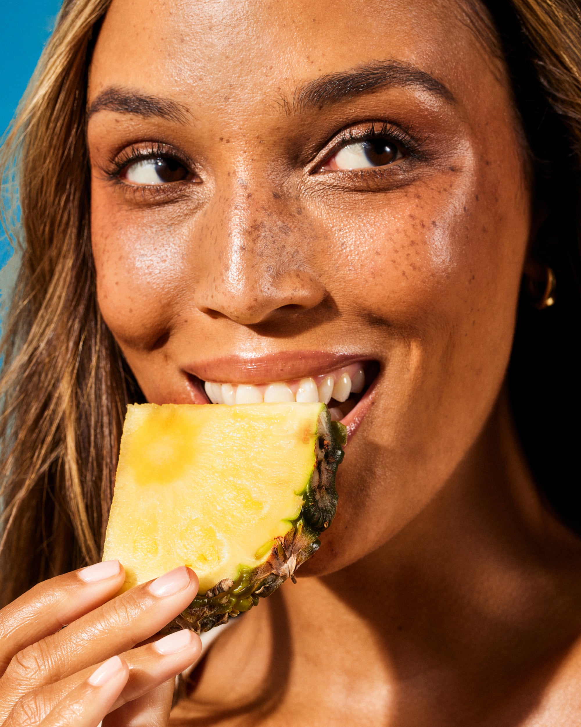 Daily Defense supplement with radiant lips enjoying a nourishing pineapple - energizes and fuels wellness.
